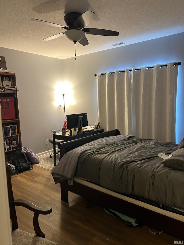 bedroom featuring hardwood / wood-style floors, a textured ceiling, and ceiling fan