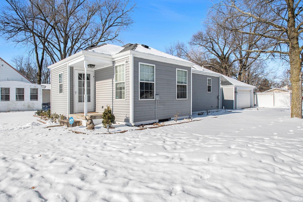 snow covered house featuring an outdoor structure and a garage