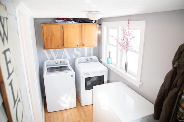 laundry room with washer and dryer, cabinets, and light wood-type flooring