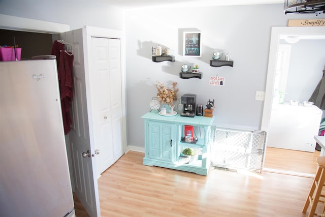 bar featuring white refrigerator and light hardwood / wood-style floors