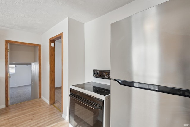 kitchen featuring a textured ceiling, light hardwood / wood-style floors, black electric range, and stainless steel fridge