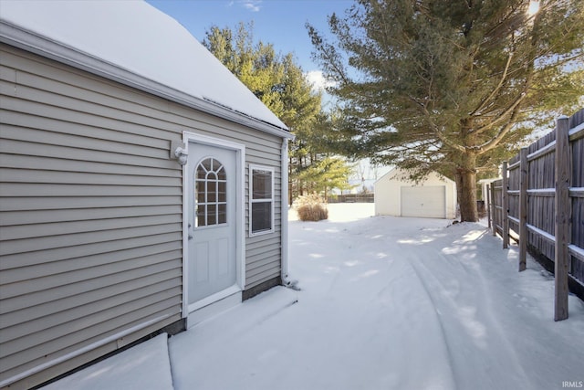 snow covered patio featuring an outbuilding and a garage