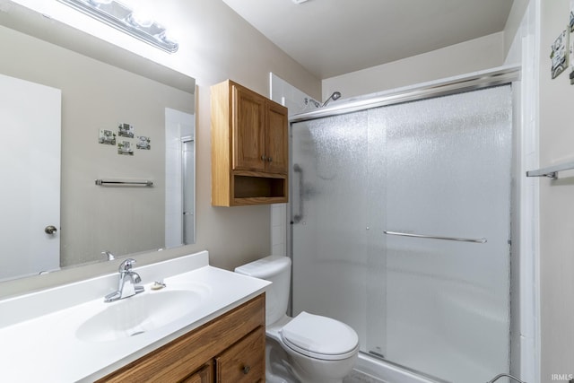 bathroom with toilet, vanity, and an enclosed shower