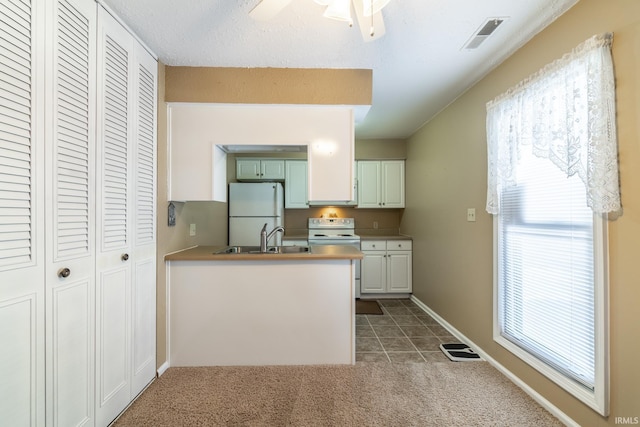 kitchen featuring sink, white appliances, white cabinets, and kitchen peninsula