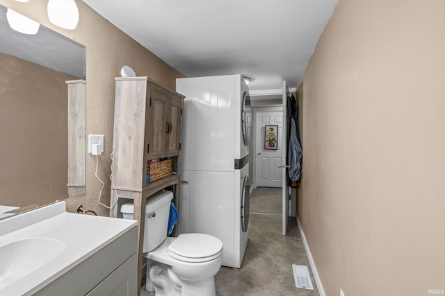 bathroom with toilet, stacked washer / drying machine, and vanity