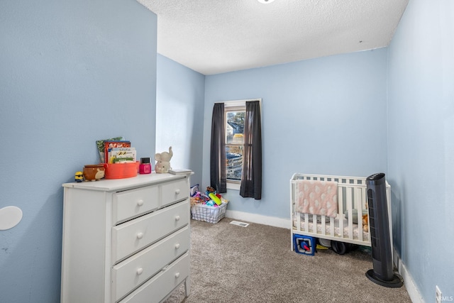 carpeted bedroom with a nursery area and a textured ceiling