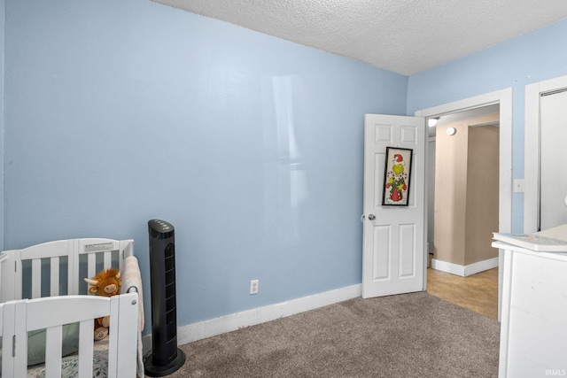 unfurnished bedroom featuring carpet, a textured ceiling, and a crib