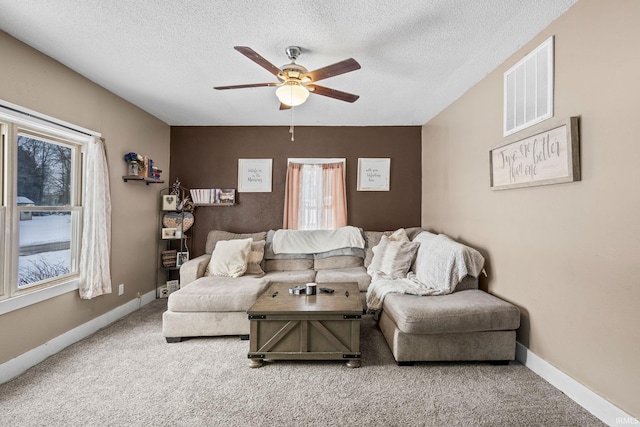 carpeted living room featuring ceiling fan and a textured ceiling