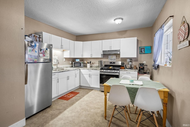 kitchen with sink, stainless steel appliances, a textured ceiling, light carpet, and white cabinets