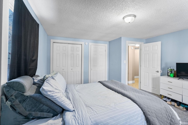 carpeted bedroom featuring two closets and a textured ceiling