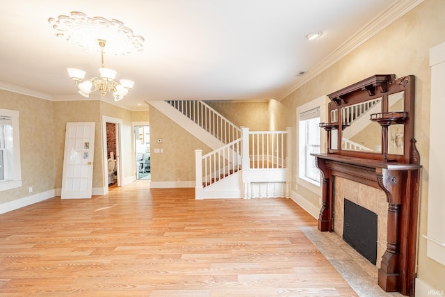 unfurnished living room with ornamental molding, light hardwood / wood-style floors, a tile fireplace, and a chandelier