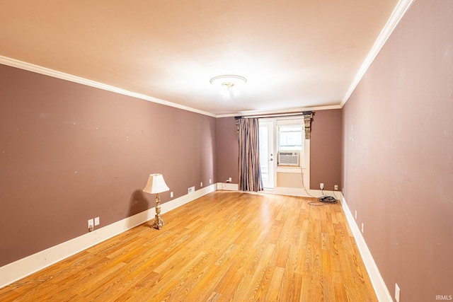 empty room featuring cooling unit, light hardwood / wood-style flooring, and ornamental molding