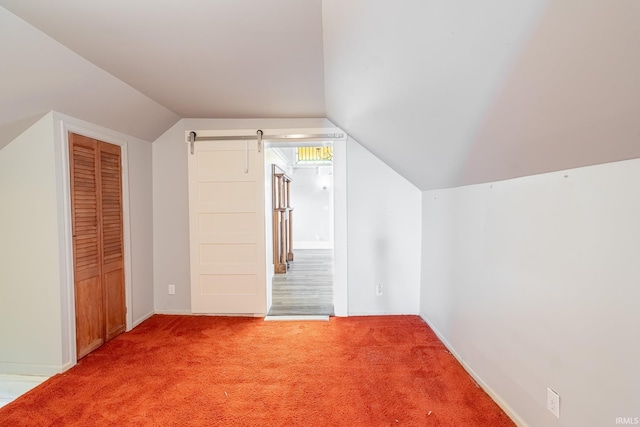 bonus room with vaulted ceiling, carpet flooring, and a barn door