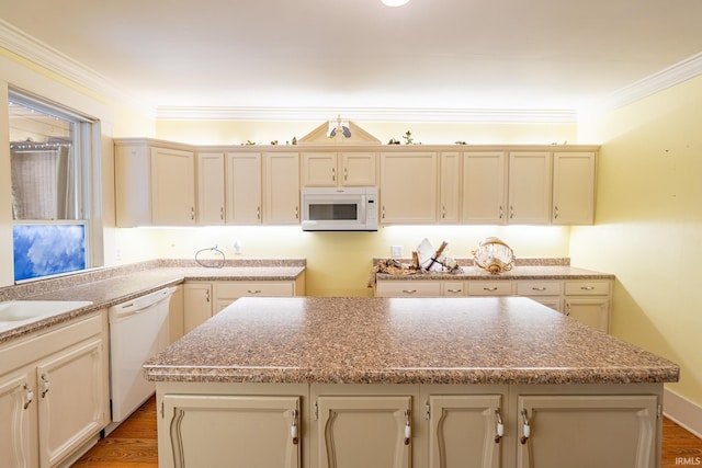 kitchen with hardwood / wood-style floors, a center island, white appliances, and cream cabinets