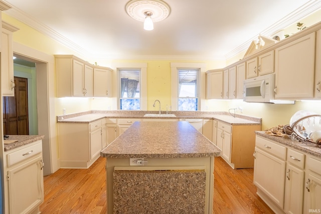 kitchen featuring a kitchen island, sink, white appliances, light wood-type flooring, and cream cabinetry