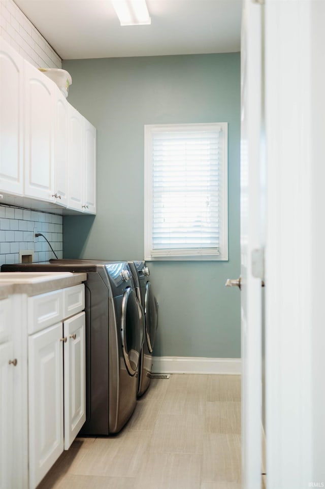 washroom with cabinets, sink, and washing machine and dryer