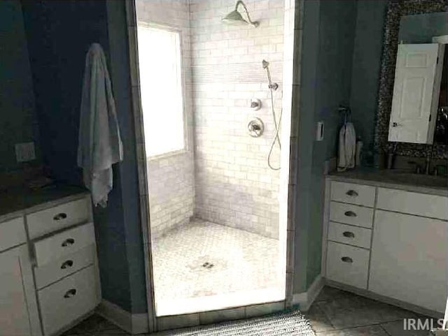 bathroom featuring tile patterned flooring, vanity, and a tile shower