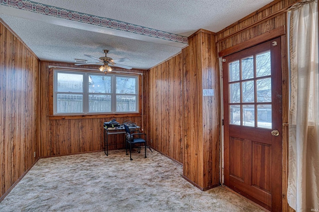 interior space with a healthy amount of sunlight, light colored carpet, and wood walls