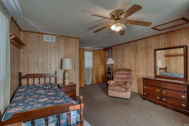 carpeted bedroom featuring ceiling fan, wooden walls, ornamental molding, and a textured ceiling