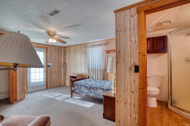 bedroom with light carpet, wooden walls, ornamental molding, and a textured ceiling