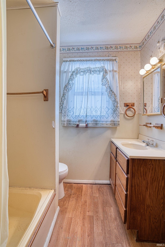 bathroom featuring vanity, toilet, hardwood / wood-style floors, and a textured ceiling