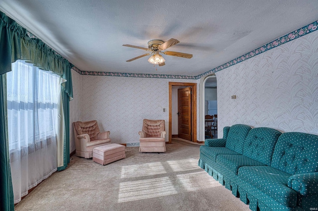 living room featuring carpet floors, a textured ceiling, and ceiling fan