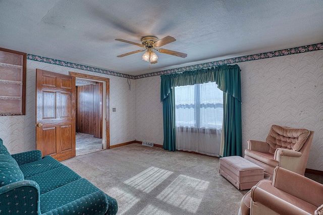 living room featuring light carpet, ceiling fan, and a textured ceiling