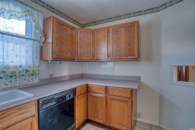 kitchen featuring black dishwasher, sink, and a textured ceiling