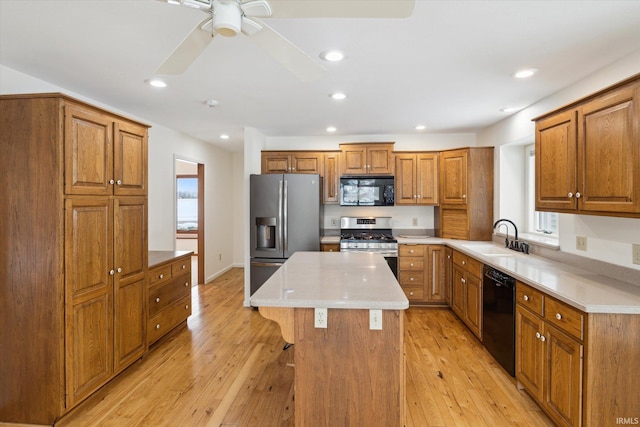 kitchen with black appliances, a kitchen island, sink, light hardwood / wood-style flooring, and a breakfast bar area