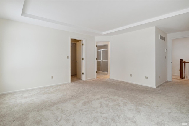 unfurnished room featuring light carpet and a tray ceiling