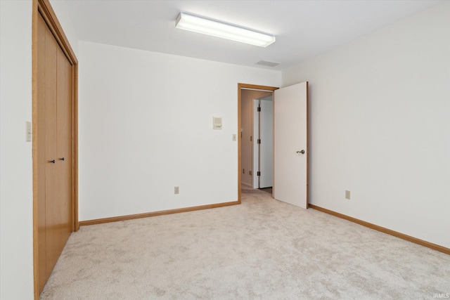 unfurnished bedroom featuring a closet and light colored carpet