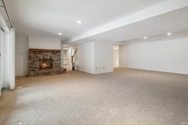 unfurnished living room with a brick fireplace and light colored carpet