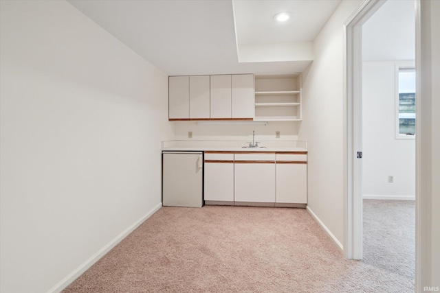 kitchen featuring light colored carpet, white cabinets, fridge, and sink