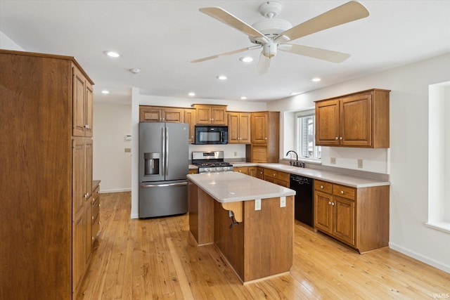 kitchen featuring a kitchen bar, a kitchen island, black appliances, light hardwood / wood-style flooring, and sink