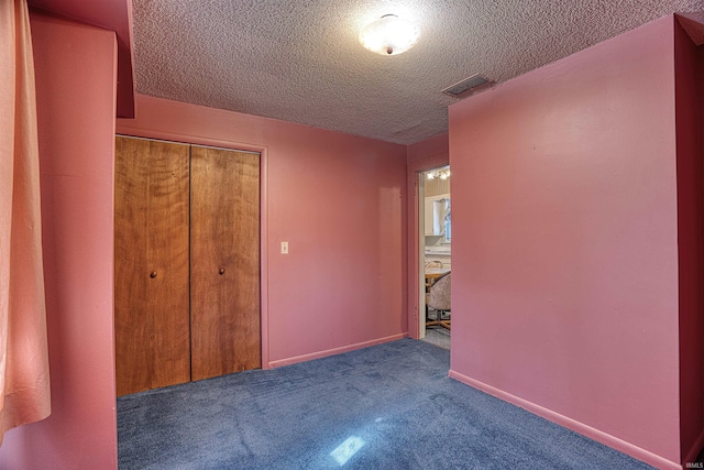 unfurnished bedroom featuring a textured ceiling, a closet, and dark colored carpet