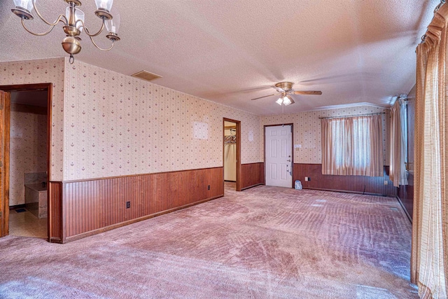 unfurnished room with a textured ceiling, carpet flooring, and ceiling fan with notable chandelier