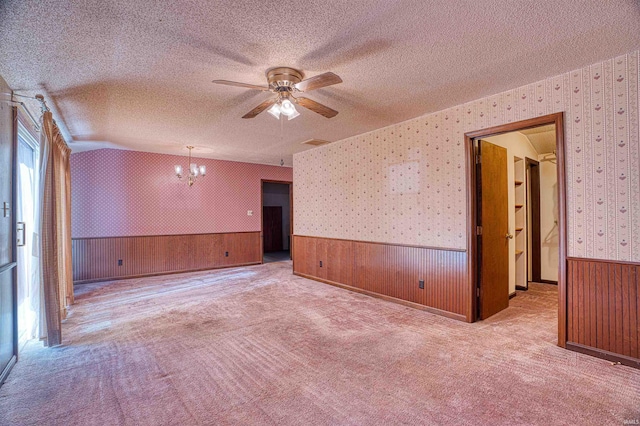 empty room with light colored carpet and ceiling fan with notable chandelier