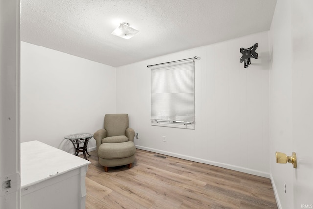 sitting room featuring light hardwood / wood-style floors and a textured ceiling