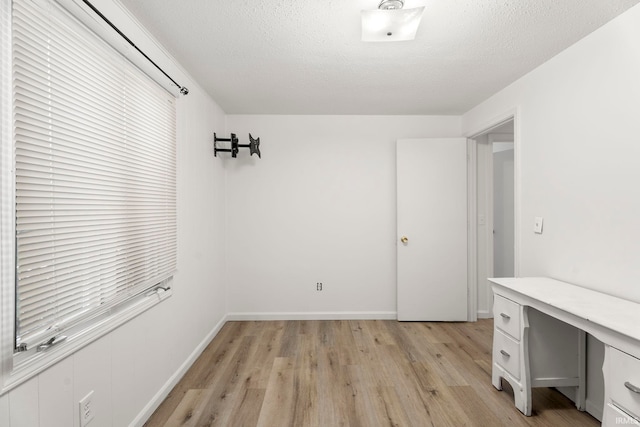 unfurnished office with light hardwood / wood-style floors and a textured ceiling