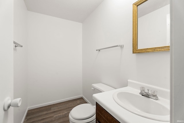 bathroom with hardwood / wood-style floors, toilet, vanity, and a textured ceiling