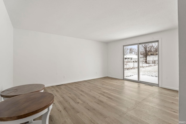 empty room featuring a textured ceiling and light wood-type flooring