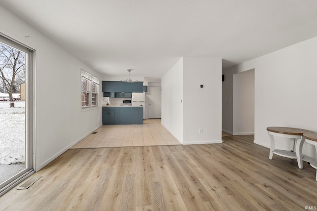 unfurnished living room featuring a chandelier and light hardwood / wood-style floors