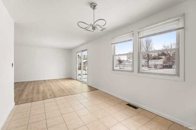 unfurnished room featuring light tile patterned floors and an inviting chandelier