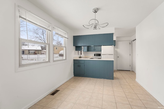 kitchen with pendant lighting, kitchen peninsula, blue cabinetry, white refrigerator, and a chandelier