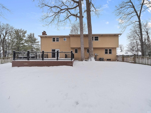 snow covered rear of property with central AC unit and a deck