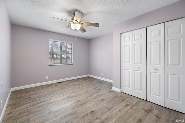 unfurnished bedroom featuring a textured ceiling, ceiling fan, a closet, and light hardwood / wood-style floors