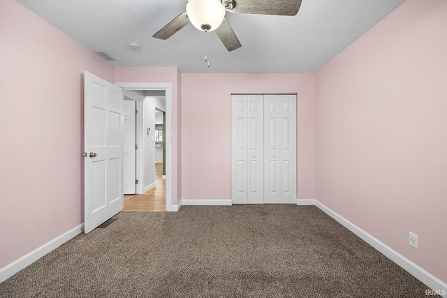 unfurnished bedroom with ceiling fan, light colored carpet, a closet, and a textured ceiling