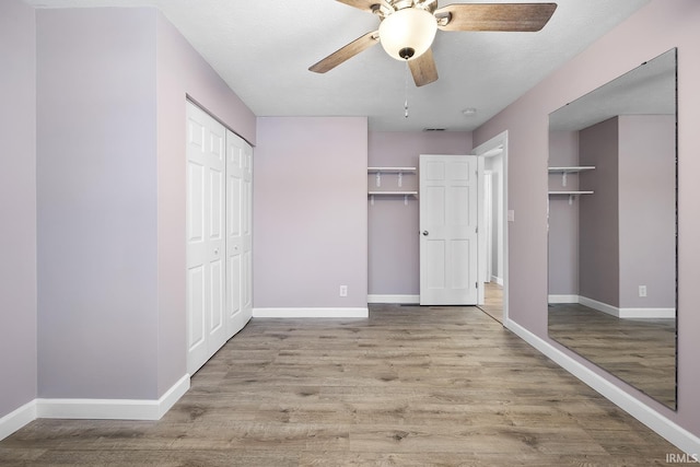 unfurnished bedroom with ceiling fan, multiple closets, and light wood-type flooring