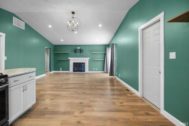 living room featuring vaulted ceiling, a notable chandelier, a textured ceiling, and light hardwood / wood-style floors