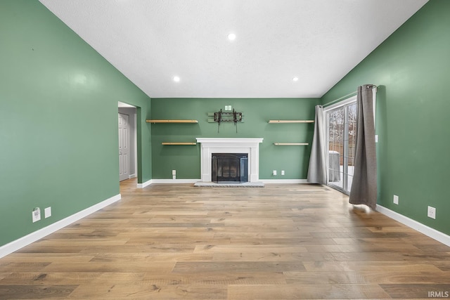 unfurnished living room featuring vaulted ceiling, a textured ceiling, and light hardwood / wood-style floors